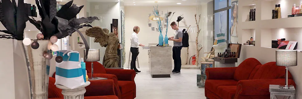 Empfang im Salon Pöpperling mit roten Sofas, türkisen Vasen und der Theke